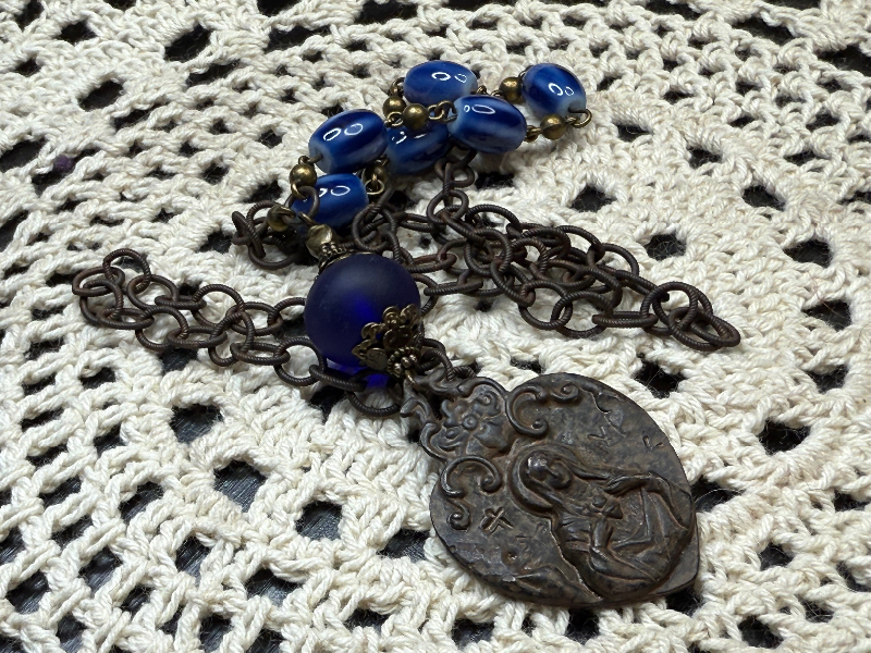 rustic, religious figure blue glass necklace